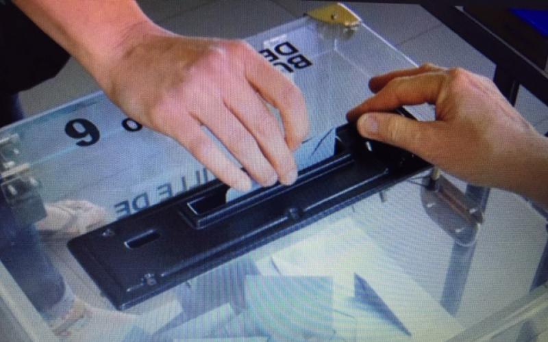Mains déposant un bulletin dans l'urne lors des élections CSE